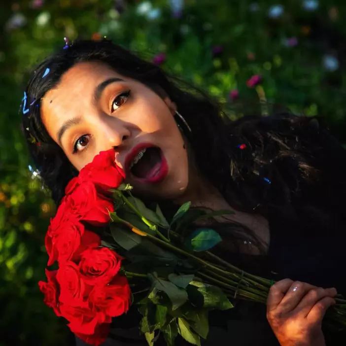 Mujer sonriendo con ramo de rosas rojas