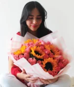 Mujer con ramo de flores de girasoles con rosas rosas