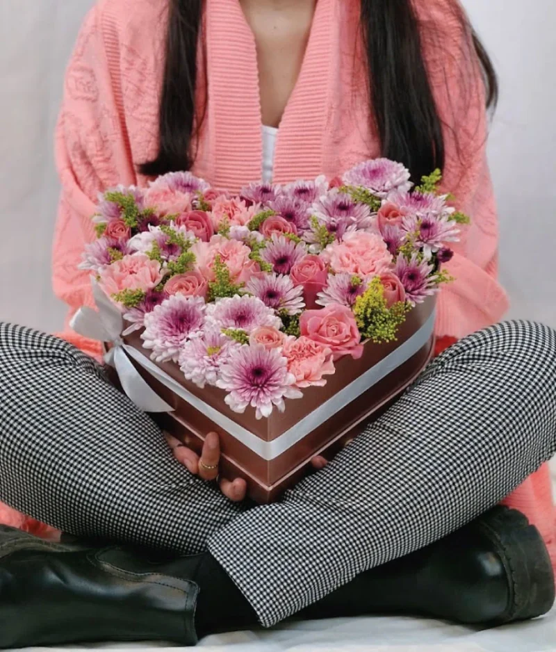 Mujer con regalo forma de corazón flores rosas