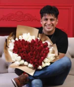 hombre sonriente sosteniendo un ramo de rosas rojas en forma de corazón