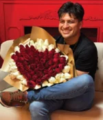 hombre sonriente sosteniendo un ramo de rosas rojas en forma de corazón