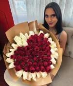 mujer sonriente sosteniendo un ramo de rosas rojas en forma de corazón con fondo blanco