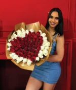 mujer sonriente sosteniendo un ramo de rosas rojas en forma de corazón con fondo blanco