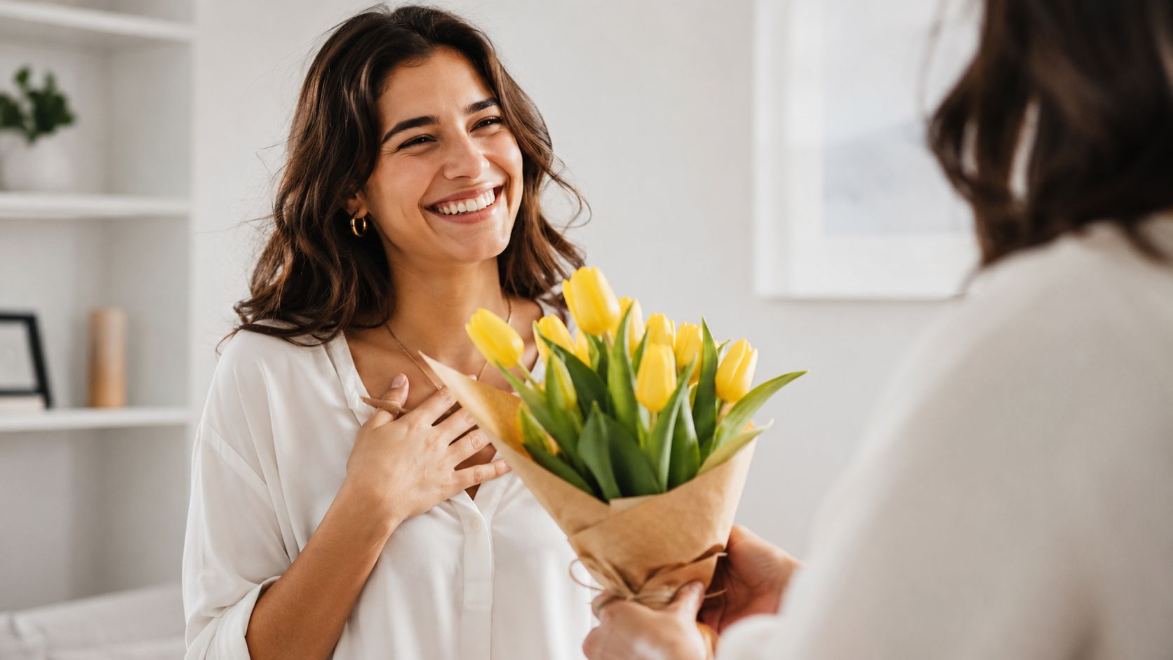 Una mujer sonriente recibe un ramo de tulipanes amarillos con emoción en una habitación iluminada