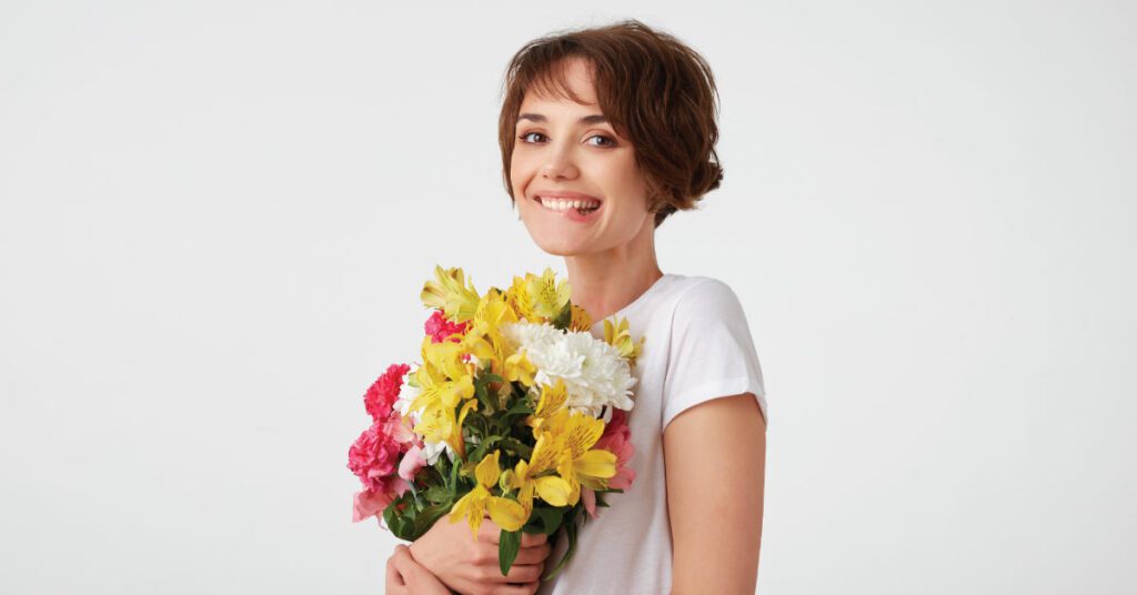 mujer sonriendo con flores y fondo blanco