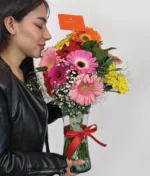 mujer oliendo ramo de gerberas