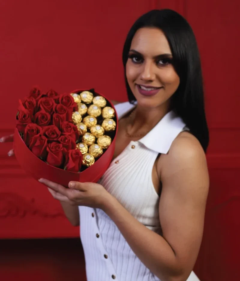 mujer sonriendo sosteniendo caja en forma de corazón con rosas y chocolates