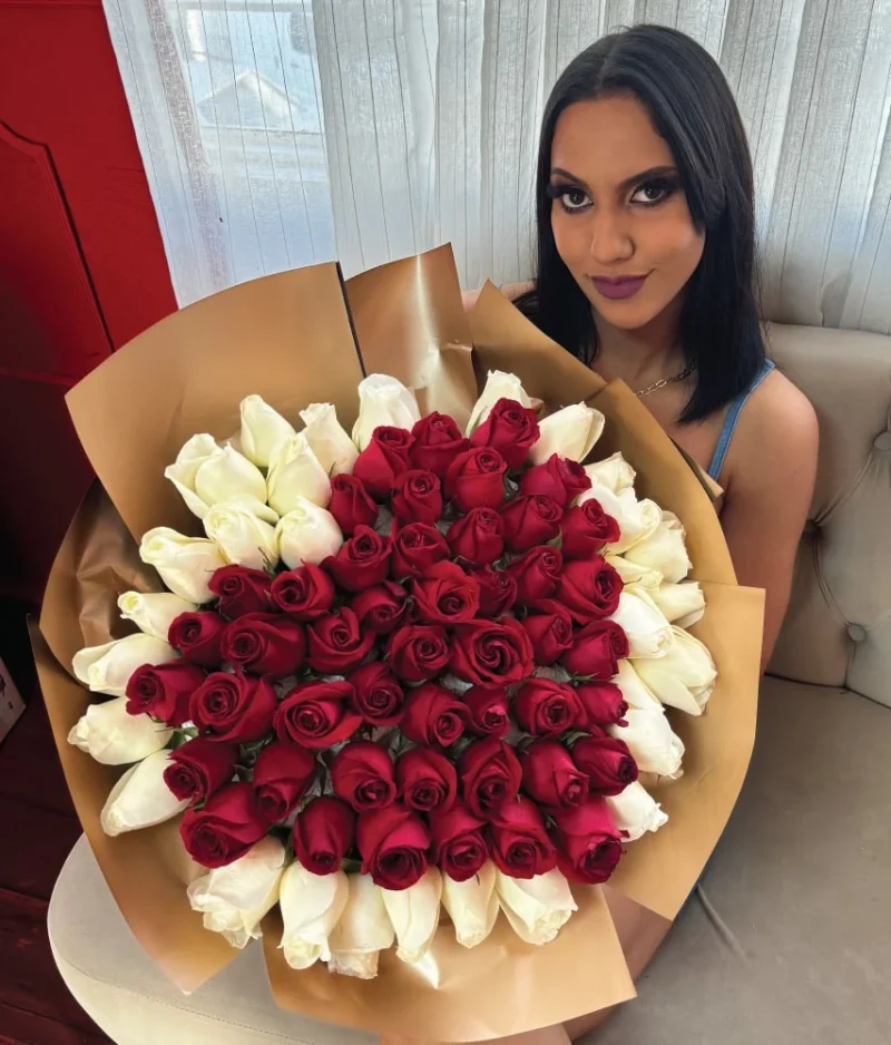 mujer sentada sosteniendo un ramo de rosas rojas en forma de corazón